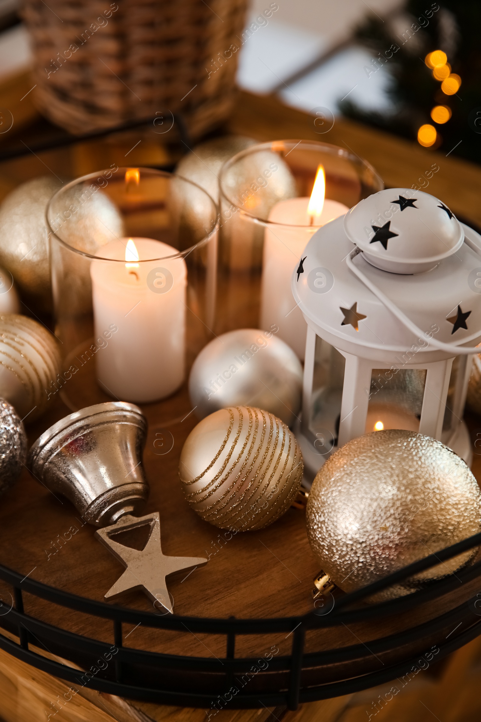 Photo of Burning candles, lantern and Christmas balls on wooden table indoors, closeup