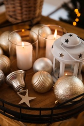 Burning candles, lantern and Christmas balls on wooden table indoors, closeup