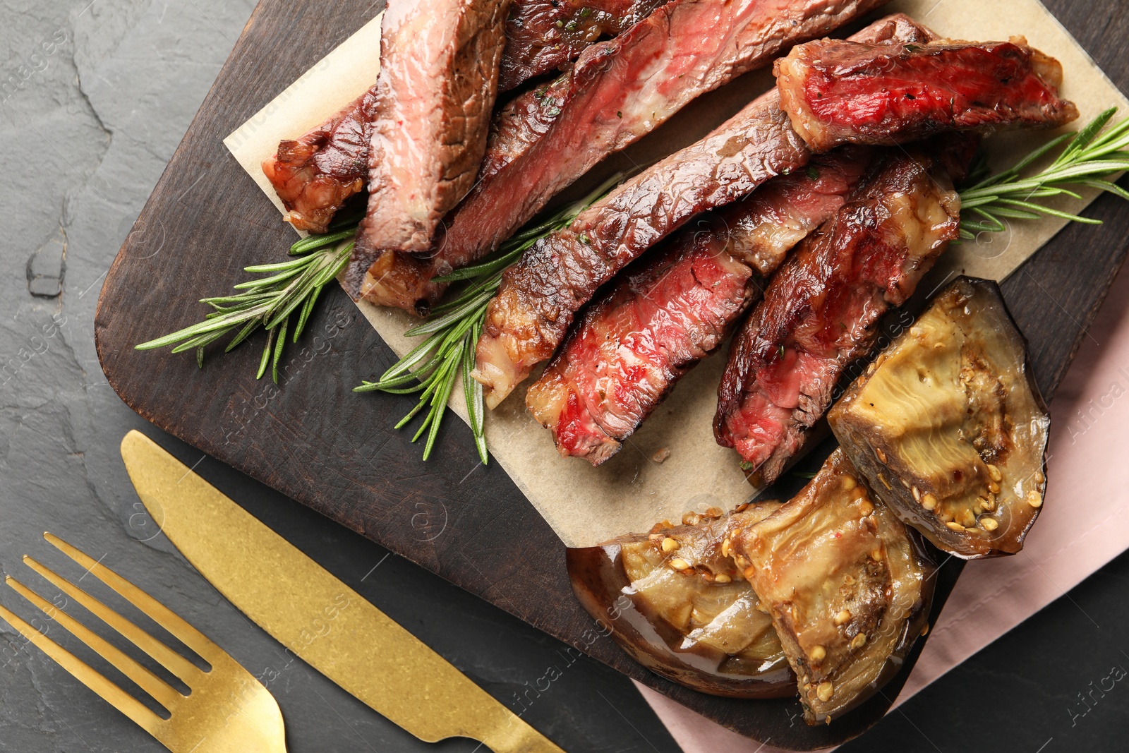 Photo of Delicious grilled beef with eggplant and rosemary served on table, top view