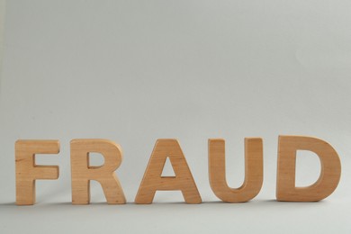 Photo of Word Fraud made of wooden letters on grey background, space for text