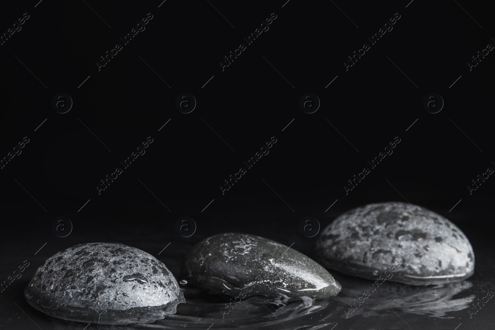 Photo of Stones in water on black background, space for text. Zen lifestyle