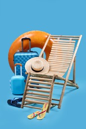 Photo of Deck chair, suitcases and beach accessories on light blue background. Summer vacation