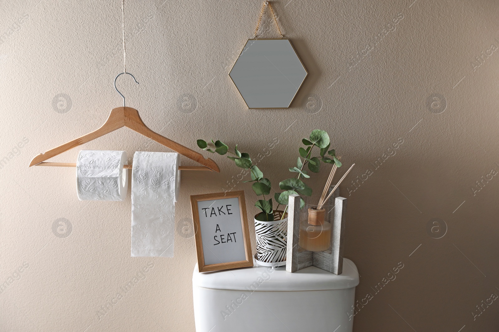 Photo of Decor elements, necessities and toilet bowl near beige wall. Bathroom interior