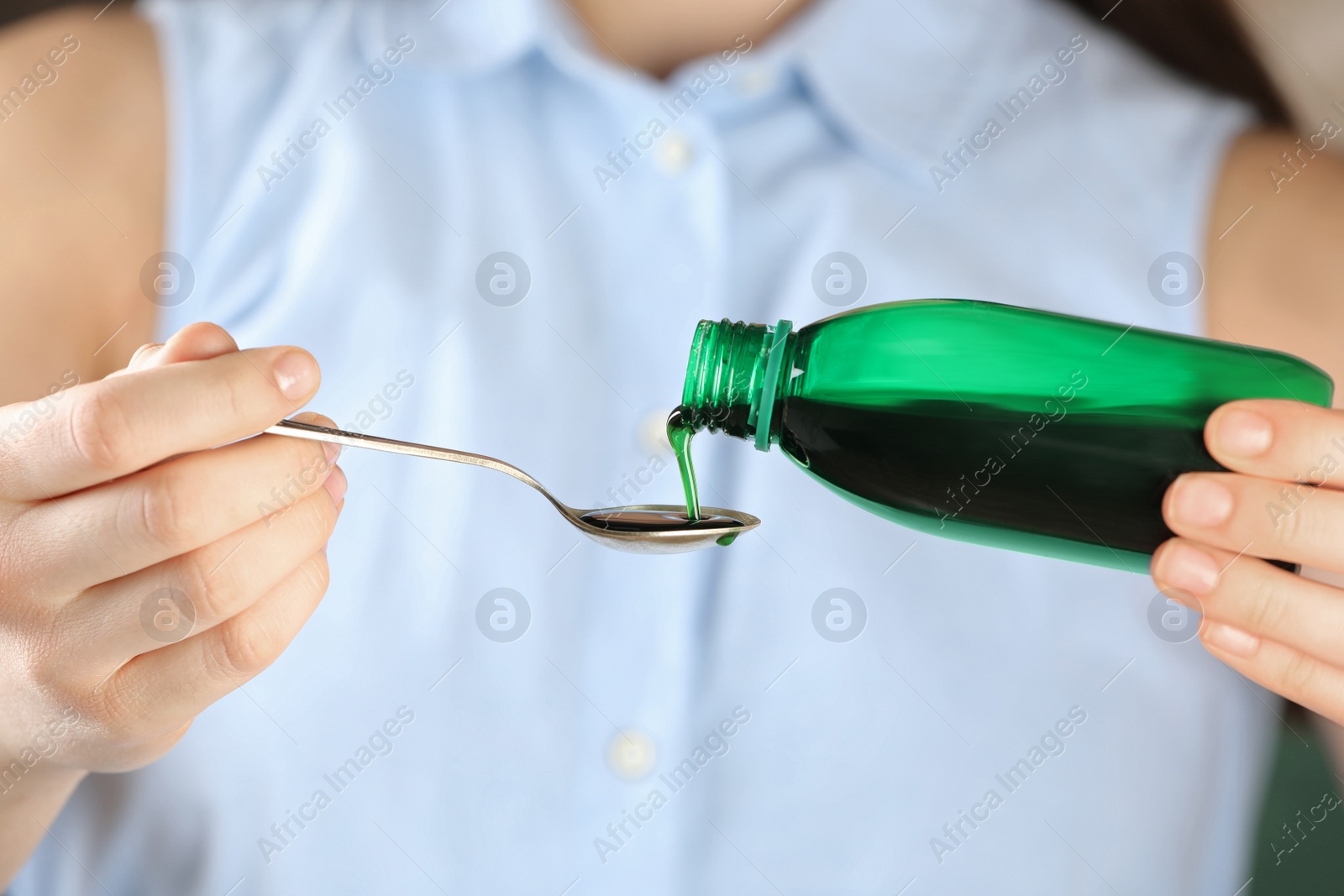 Photo of Woman pouring cough syrup into spoon, closeup