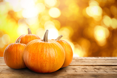 Fresh pumpkins on wooden table outdoors in autumn. Space for text