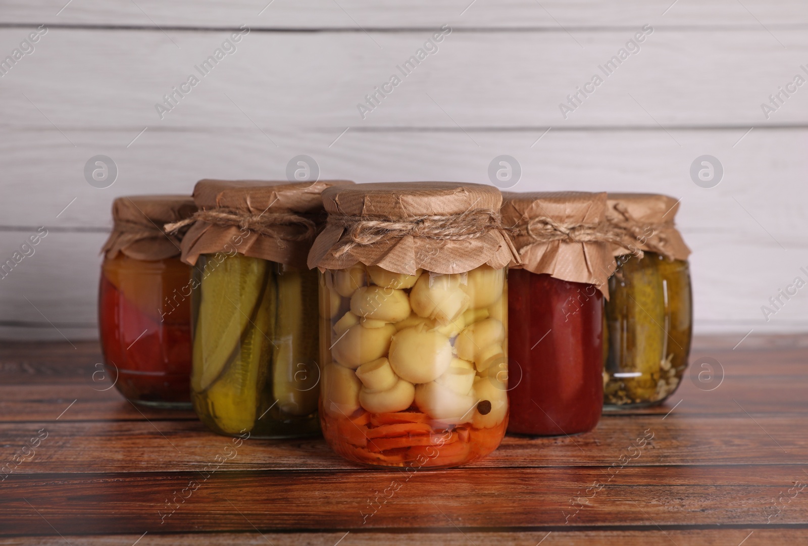 Photo of Many jars with different preserved ingredients on wooden table