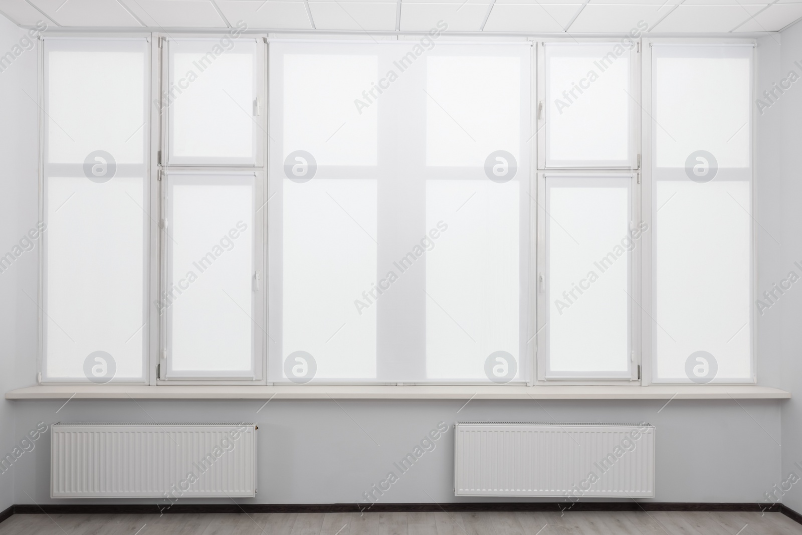 Photo of Window with closed white roller blinds indoors