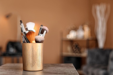 Holder with makeup brushes on table