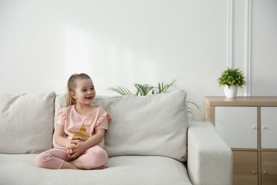Photo of Little girl resting on comfortable sofa in living room