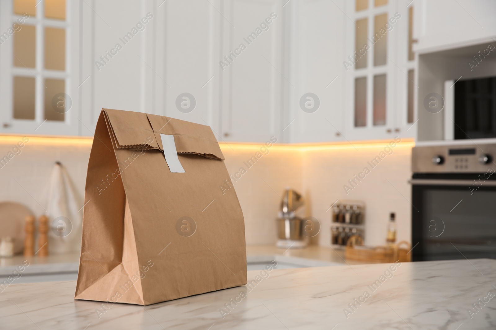 Photo of Paper bag on white marble table in kitchen. Space for text