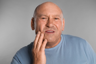 Photo of Mature man suffering from toothache on light grey background