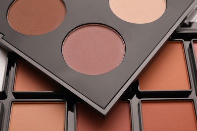 Photo of Colorful contouring palettes as background, closeup. Professional cosmetic product