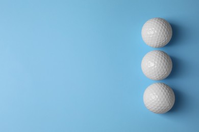 Photo of Three golf balls on light blue background, flat lay. Space for text