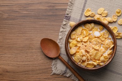 Photo of Tasty cornflakes with milk in bowl served on wooden table, flat lay. Space for text