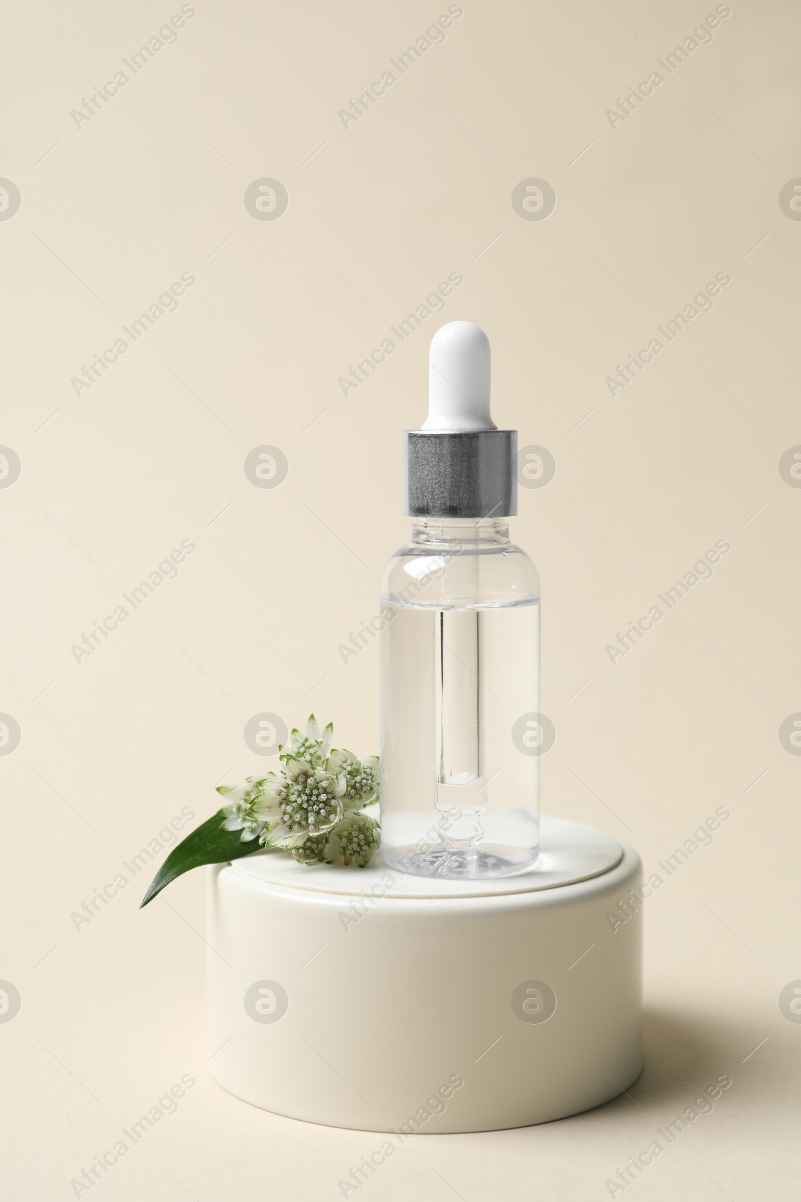 Photo of Bottle of cosmetic oil and flower on beige background