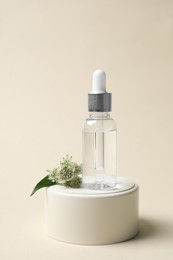 Photo of Bottle of cosmetic oil and flower on beige background