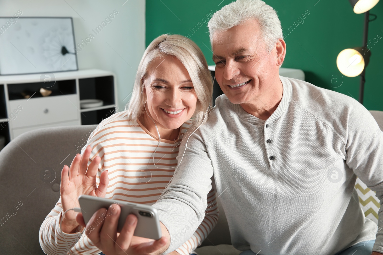 Photo of Mature couple using video chat on mobile phone at home