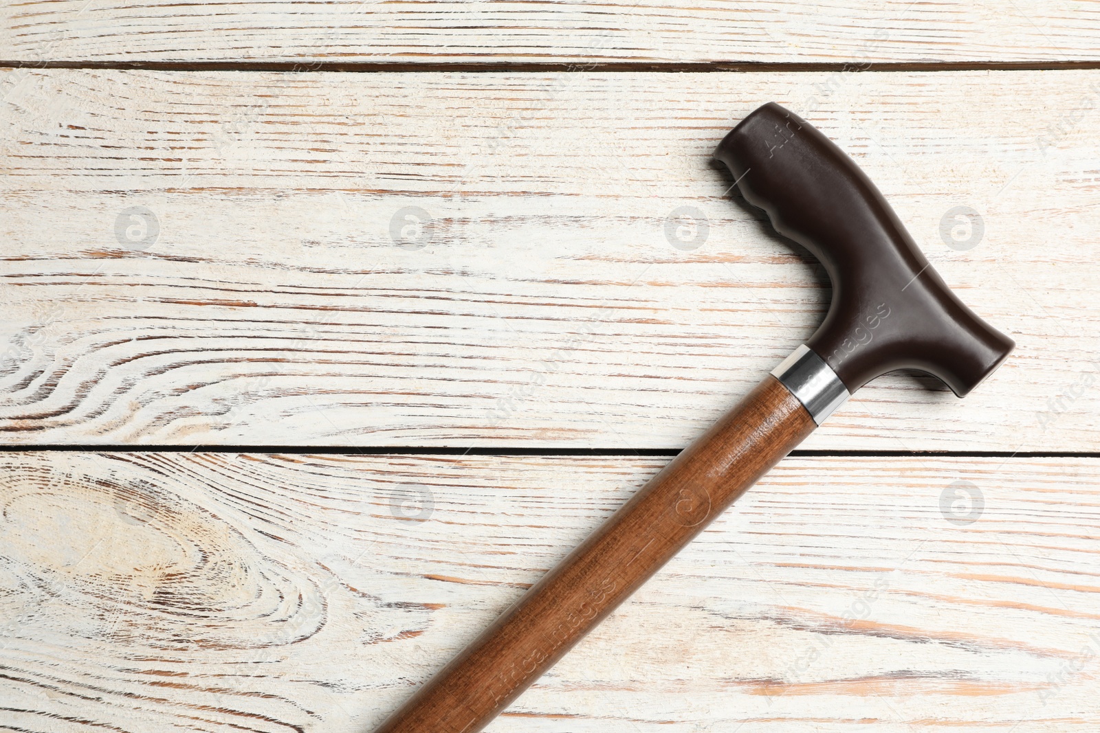 Photo of Walking cane on white wooden background, top view. Space for text