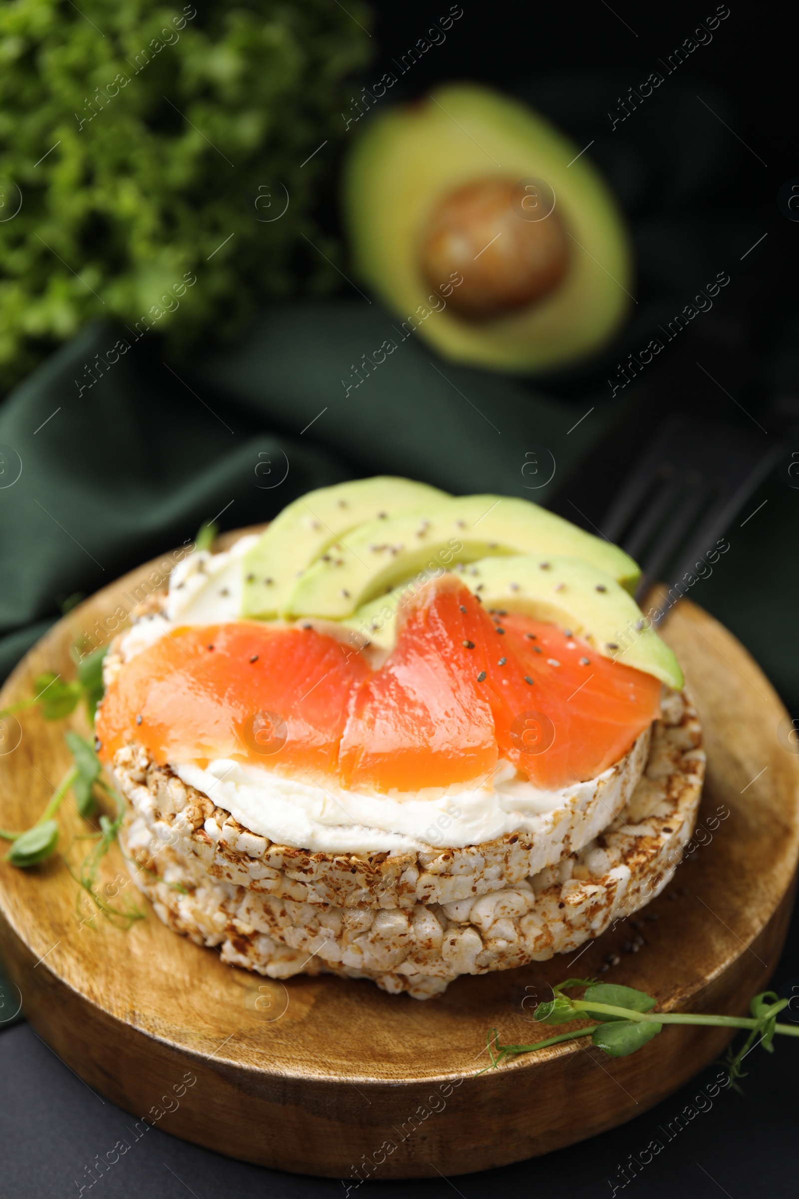 Photo of Crunchy buckwheat cakes with cream cheese, salmon and avocado on wooden board, closeup