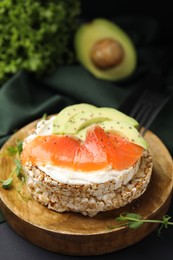 Photo of Crunchy buckwheat cakes with cream cheese, salmon and avocado on wooden board, closeup
