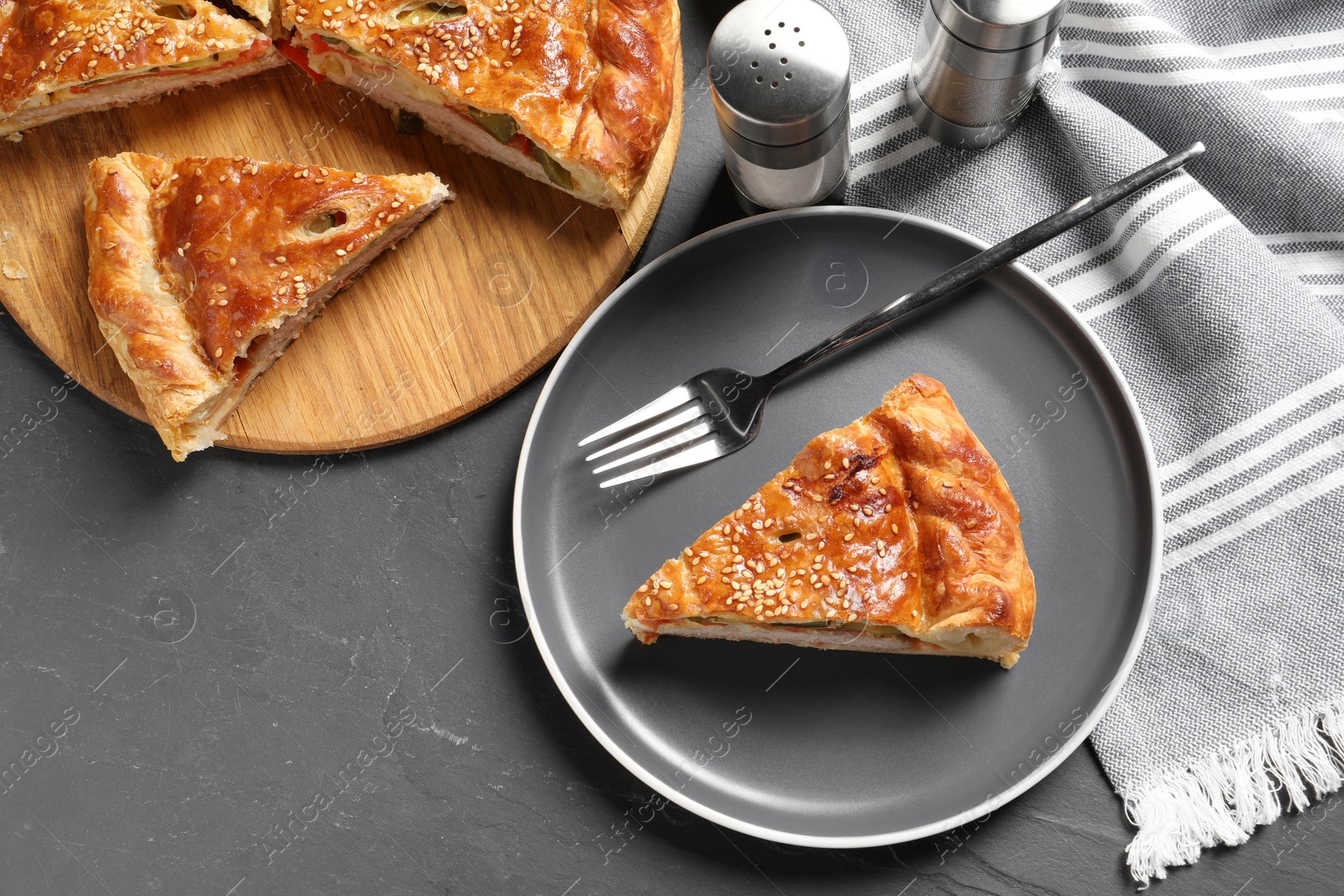 Photo of Tasty homemade pie with filling served on dark grey table, flat lay. Space for text