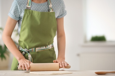 Photo of Woman rolling dough at table indoors, closeup