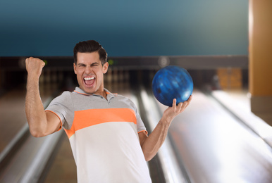 Photo of Excited man with ball in bowling club