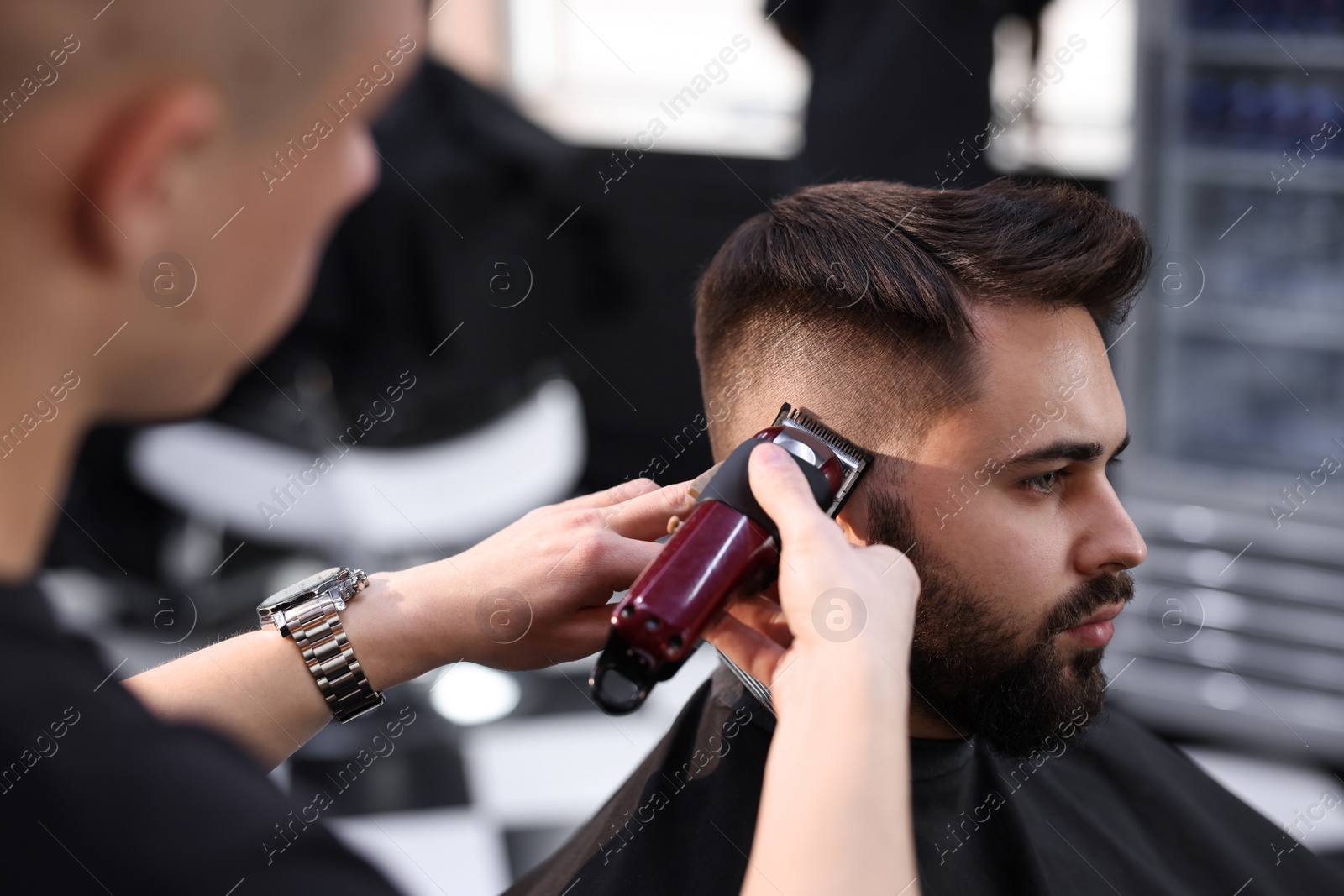 Photo of Professional hairdresser working with client in barbershop