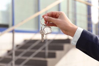 Real estate agent holding key outdoors, closeup