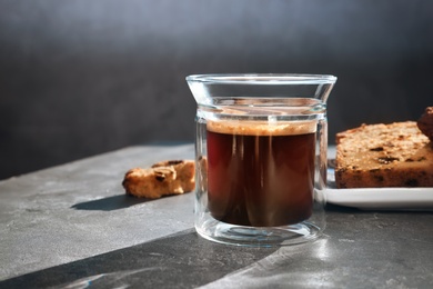 Photo of Glass of delicious coffee and plate with cake on grey table. Space for text