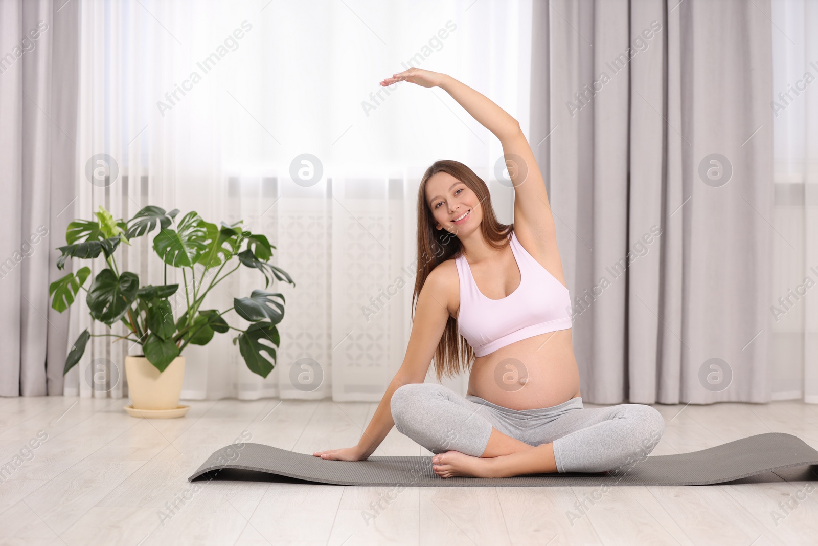Photo of Pregnant woman doing exercises on yoga mat at home