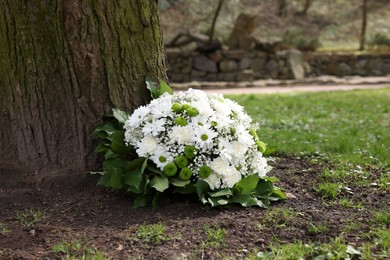 Funeral wreath of flowers near tree outdoors