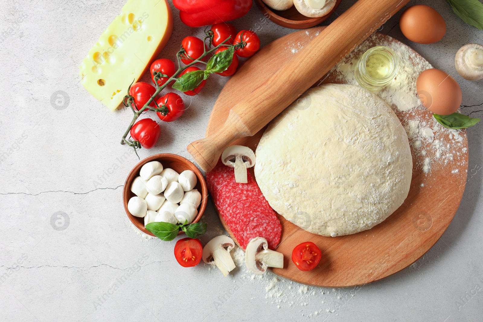 Photo of Pizza dough, products and rolling pin on gray textured table, flat lay