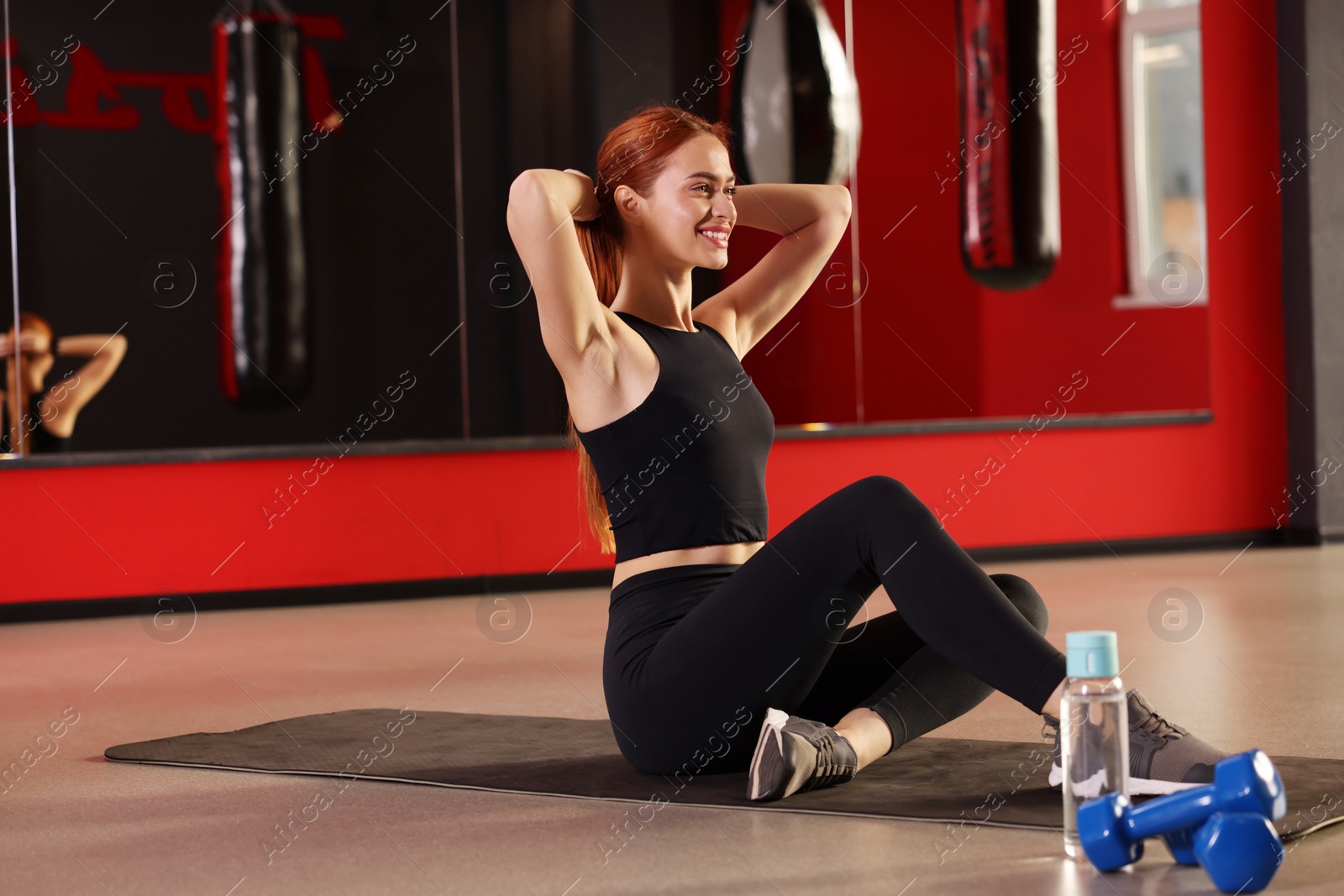 Photo of Athletic young woman doing exercise on mat in gym, space for text