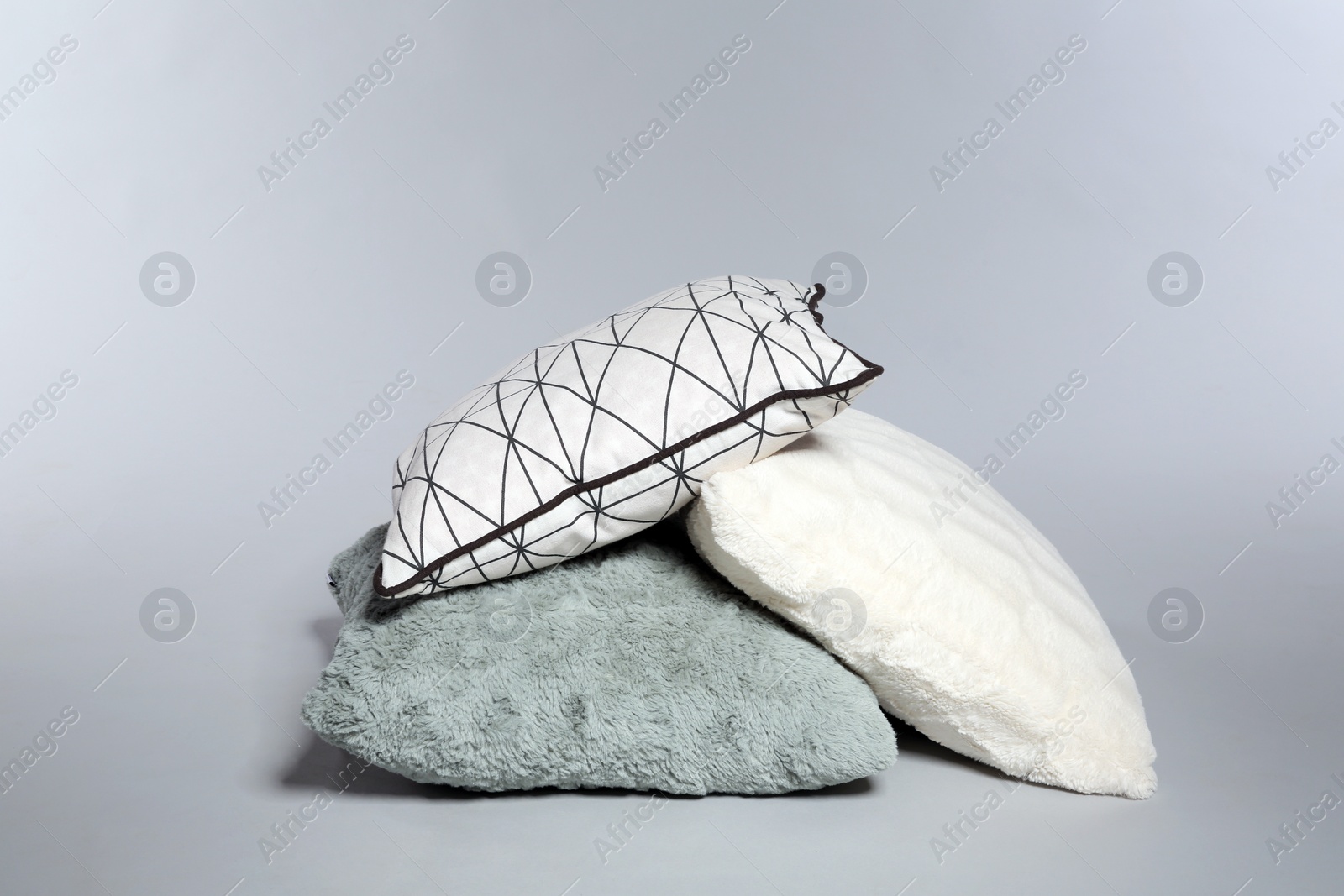 Photo of Pile of stylish decorative pillows on light background