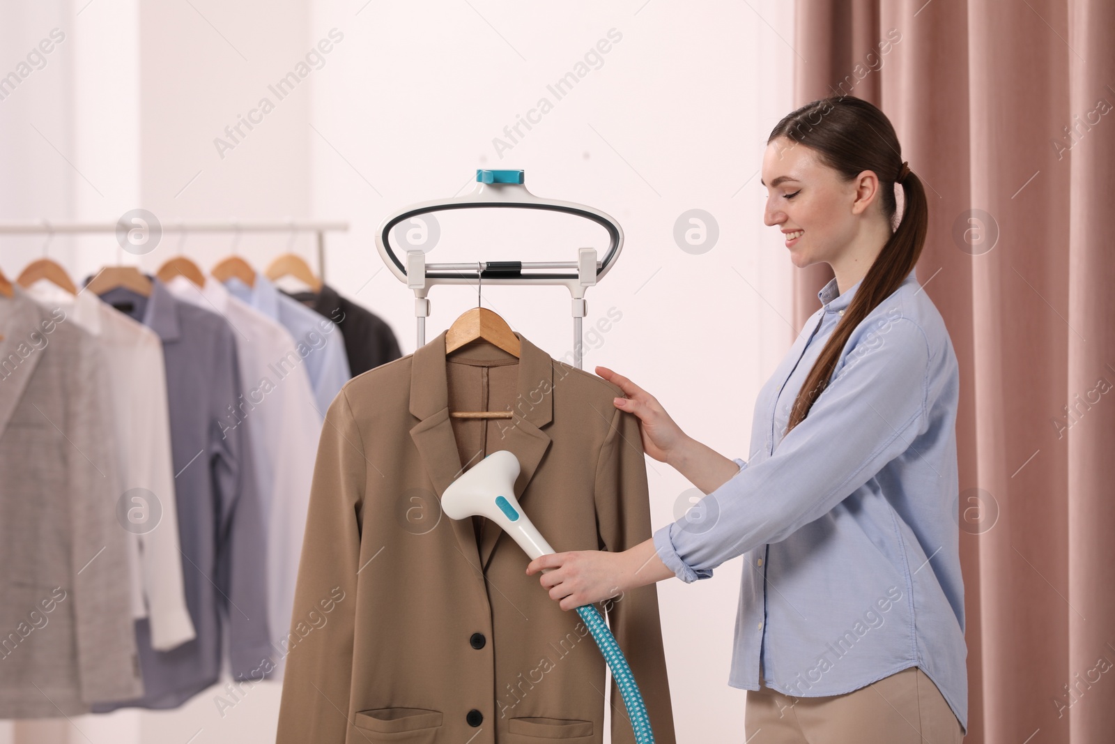 Photo of Woman steaming jacket on hanger in room