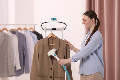 Woman steaming jacket on hanger in room