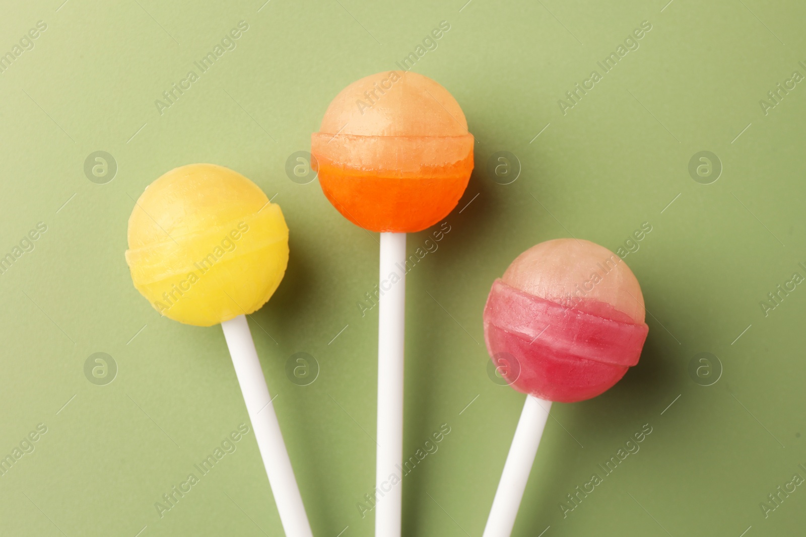 Photo of Tasty lollipops on green background, flat lay