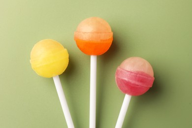 Tasty lollipops on green background, flat lay