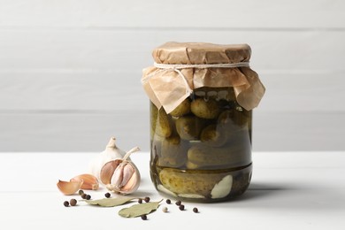 Photo of Tasty pickled cucumbers in jar and ingredients on white table