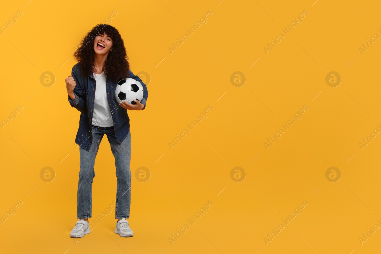 Photo of Happy fan with soccer ball celebrating on yellow background, space for text