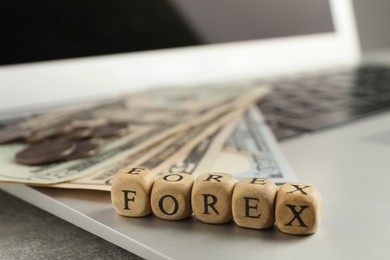Photo of Word Forex made of wooden cubes with letters on laptop, closeup