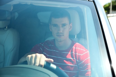 Photo of Attractive young man driving modern luxury car