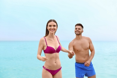 Photo of Young woman in bikini with her boyfriend on beach, space for text. Lovely couple