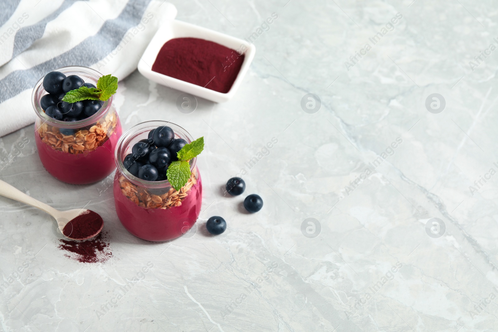 Image of Tasty dessert with acai smoothie, granola and berries on marble table. Space for text