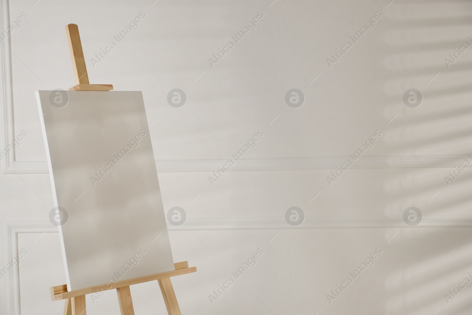 Photo of Wooden easel with blank canvas on light background. Space for text
