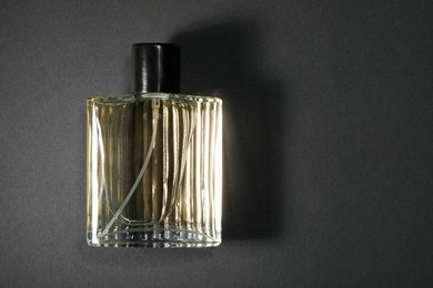 Photo of Luxury men`s perfume in bottle on black background, top view. Space for text