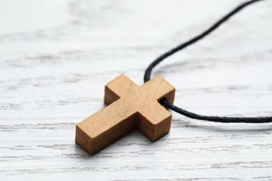 Wooden Christian cross on white table, closeup view