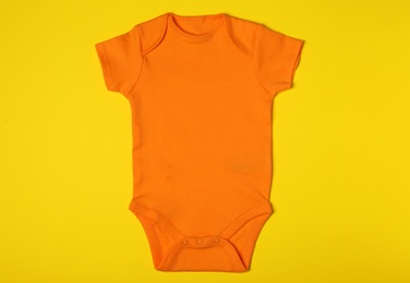 Photo of Cute baby onesie on color background, top view