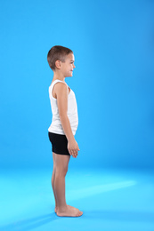 Photo of Cute little boy in underwear on light blue background